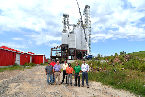 Group standing in front of feed mill under construction